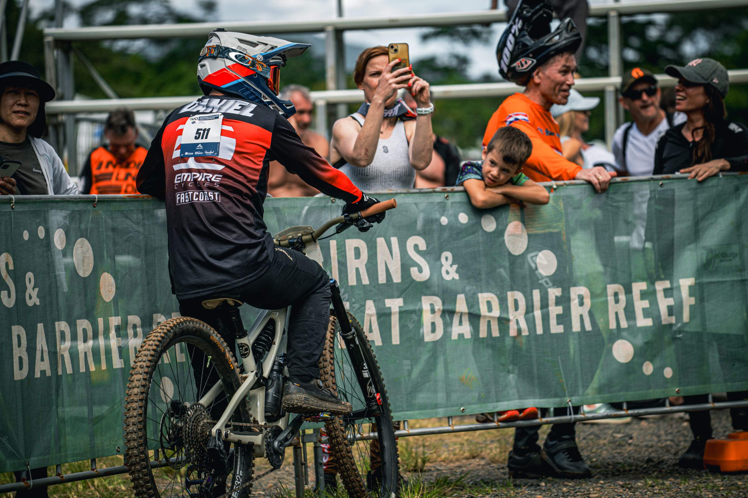 A Downhill racer leans on some Cairns and Great Barrier Reef fencing at the UCI Masters MTB World Championships in Cairns, 2025